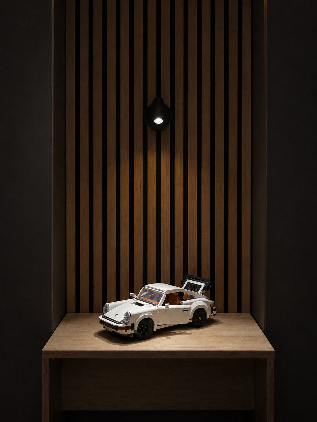 Lumivé spotlight highlighting a model car against wooden panels